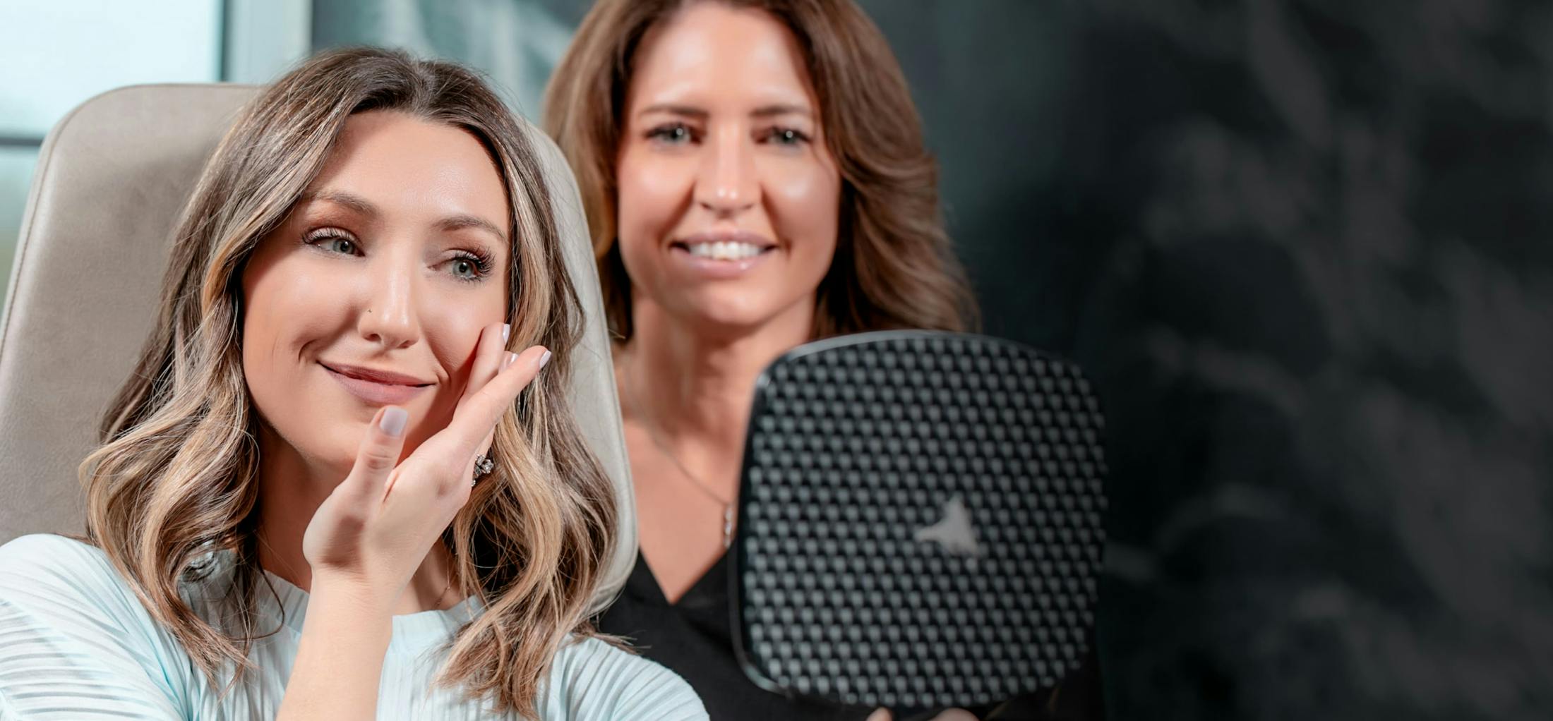 Female patient looking at herself in a handheld mirror