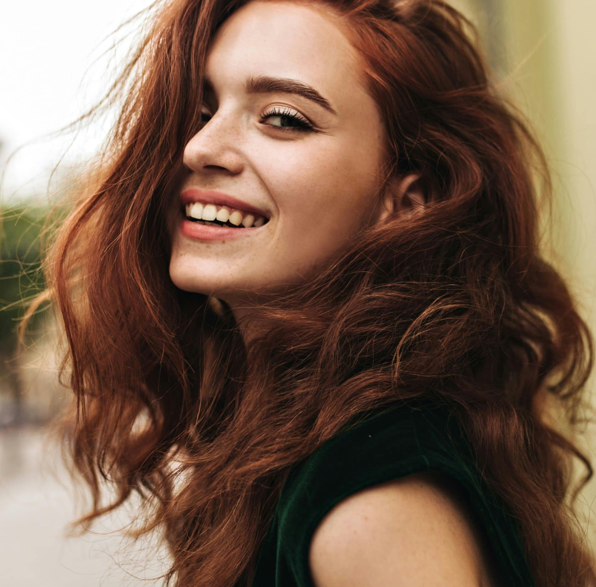 Woman with curly dark red hair smiling