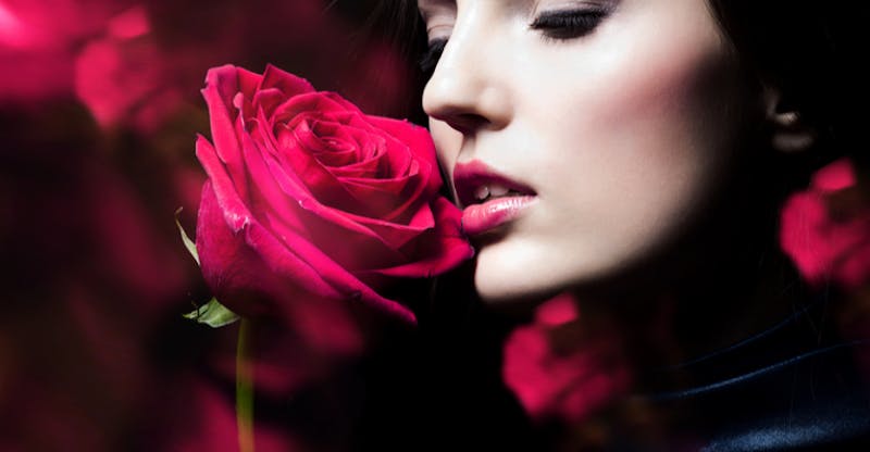 woman smelling a red rose