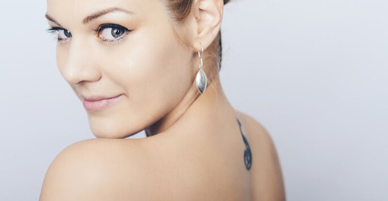 there is a woman with a tattoo on her back posing for a picture