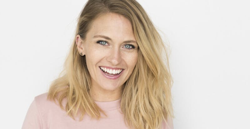 blond woman with blue eyes and a pink shirt smiling