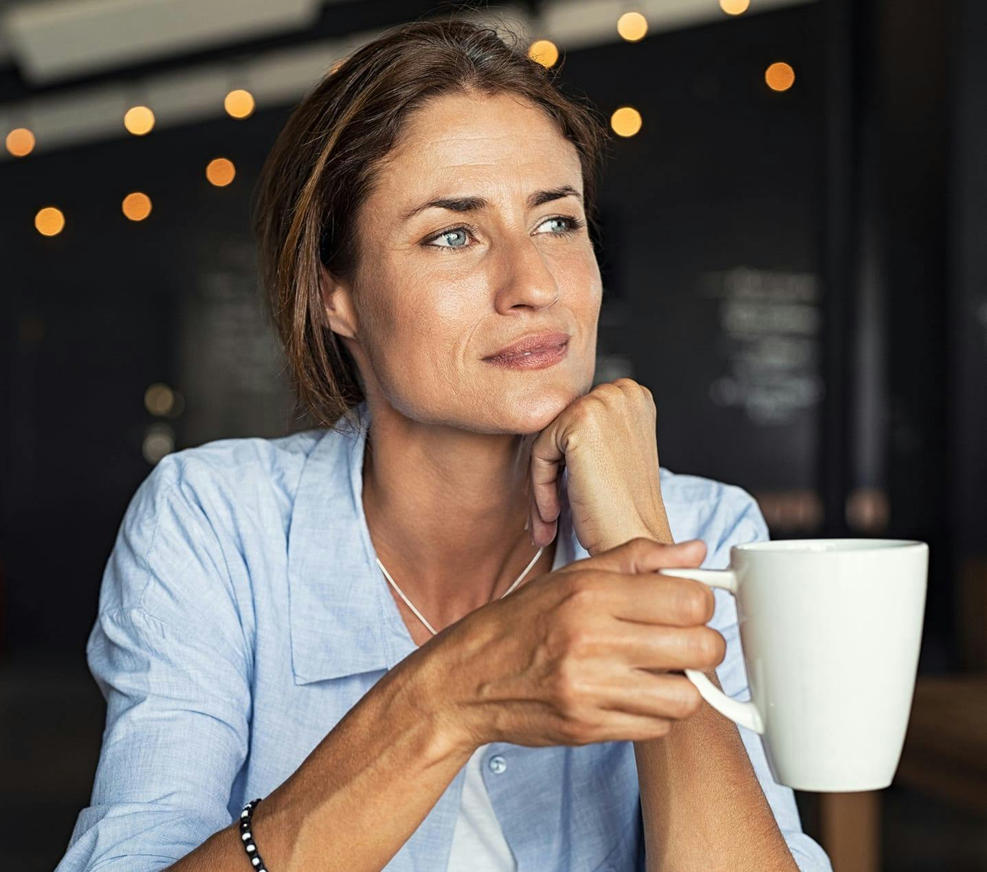 woman sitting at a table with a cup of coffee in her hand