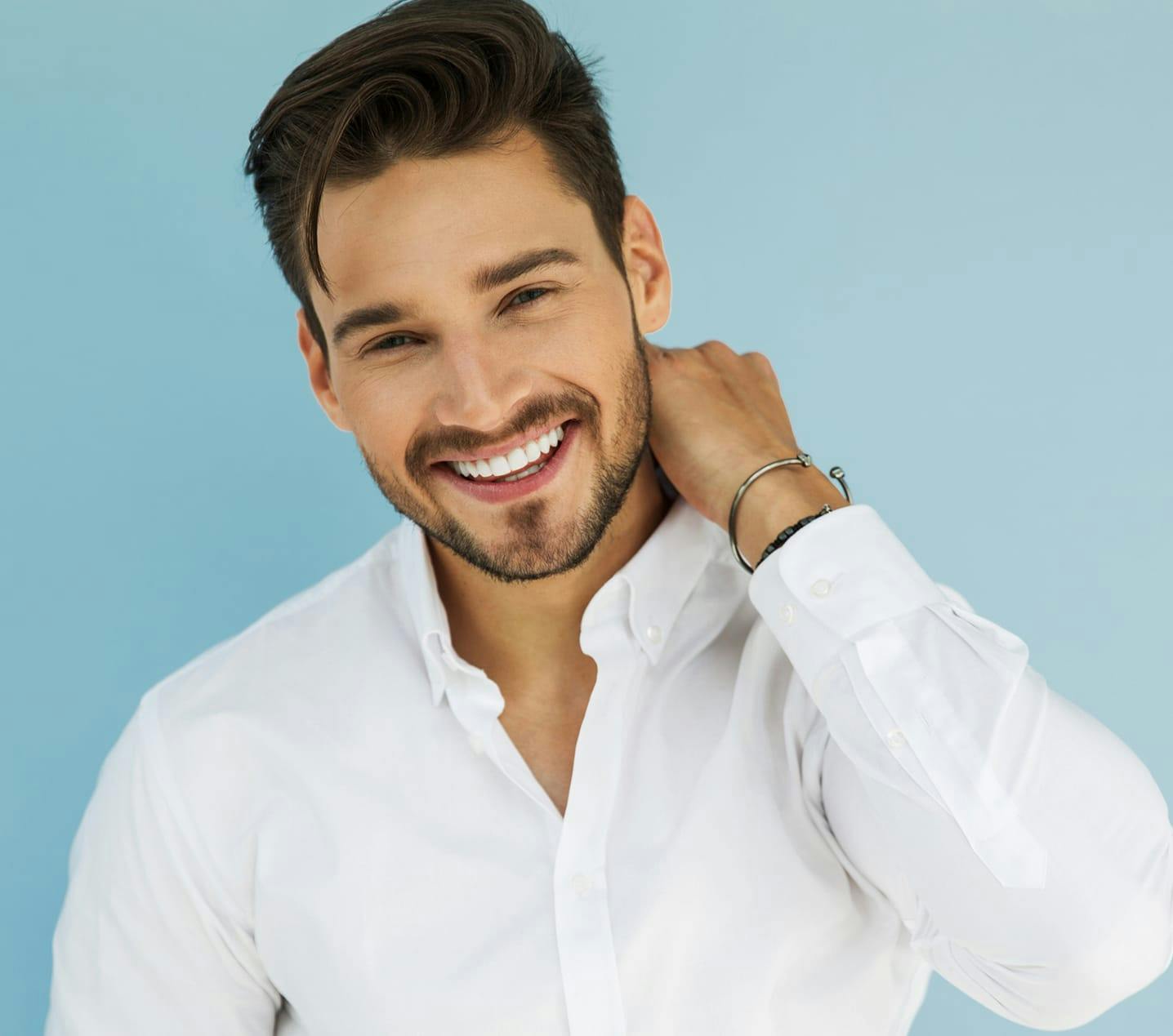 man in a white shirt smiling and holding his hand to his neck