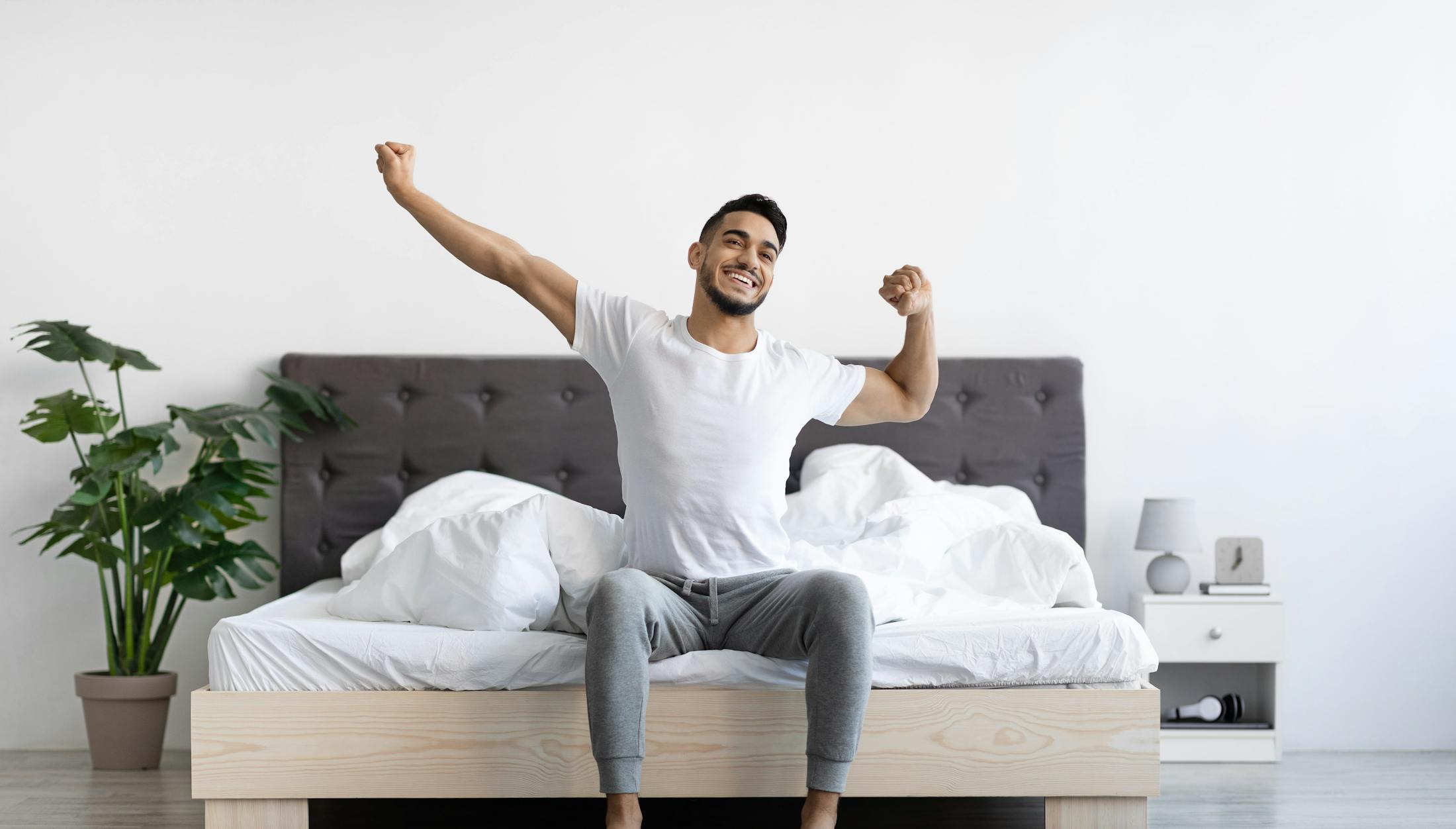 Man stretching at the end of his bed