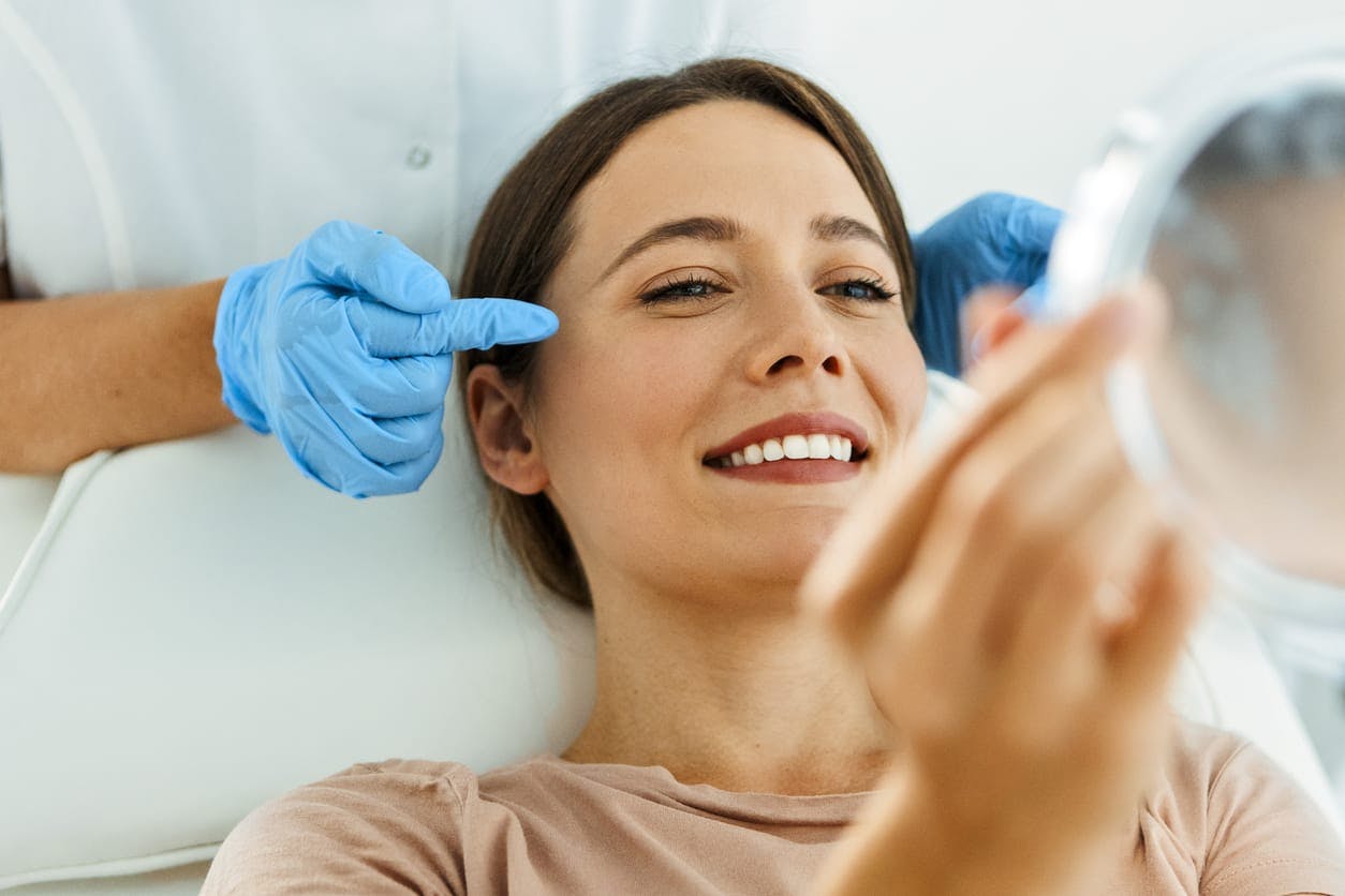 Woman smiling into mirror after a glycolic acid facial in Buffalo NY
