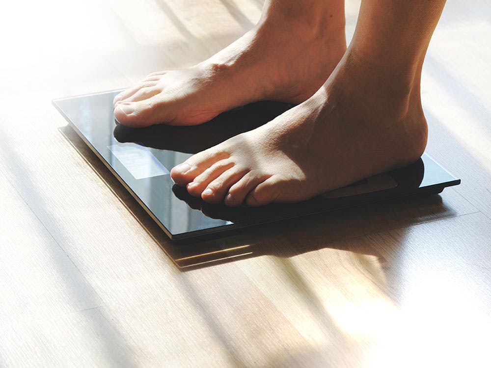 A woman weighing herself on a scale