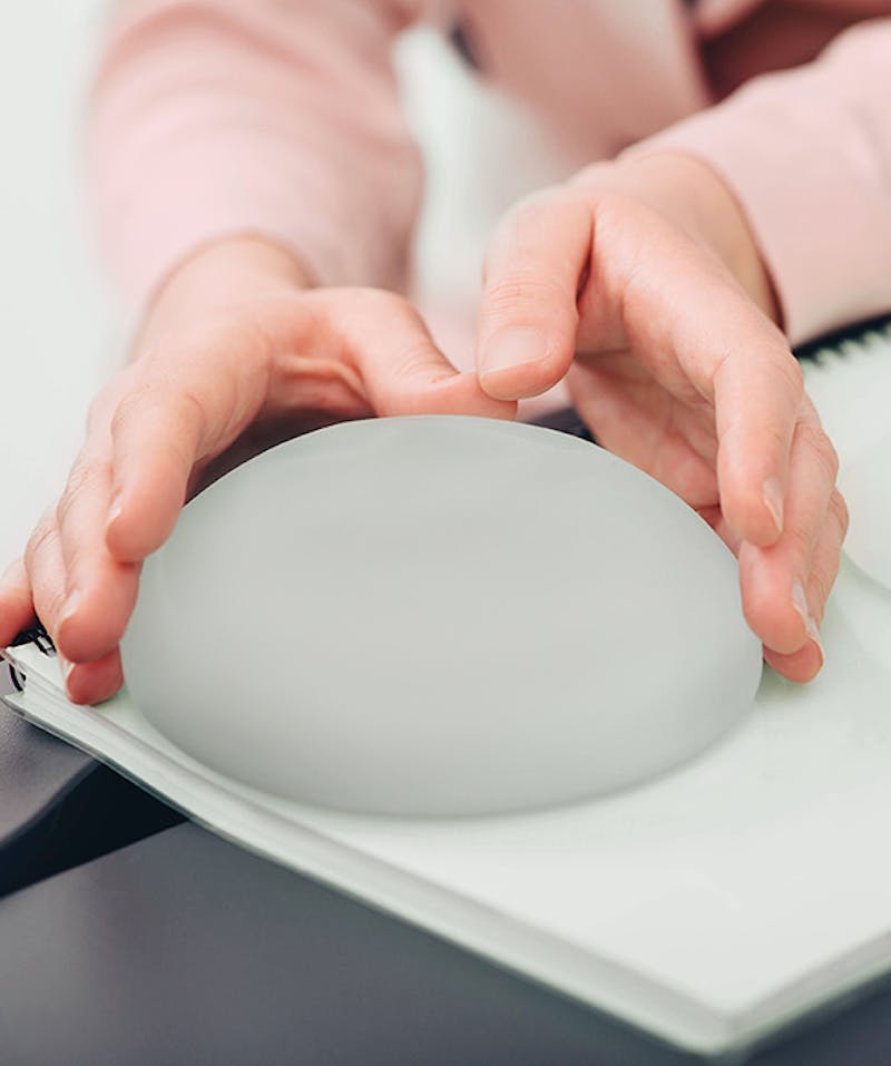 A patient examining a model breast implant