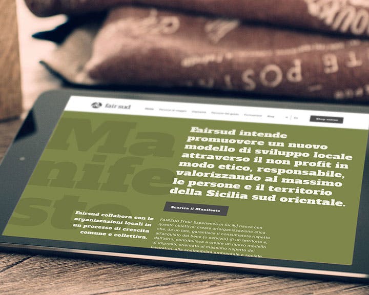 Una tavoletta nera è appoggiata su un tavolo, mostrando un sito web con un design verde oliva e un testo che promuove un modello di sviluppo locale per le organizzazioni non profit in Sicilia sud-orientale.