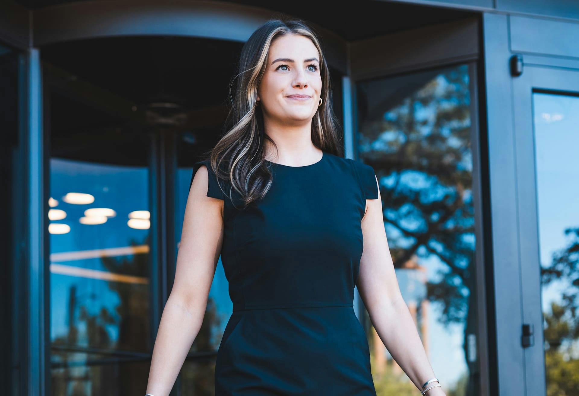 Woman in Black Dress walking out of a Revolving Glass Door