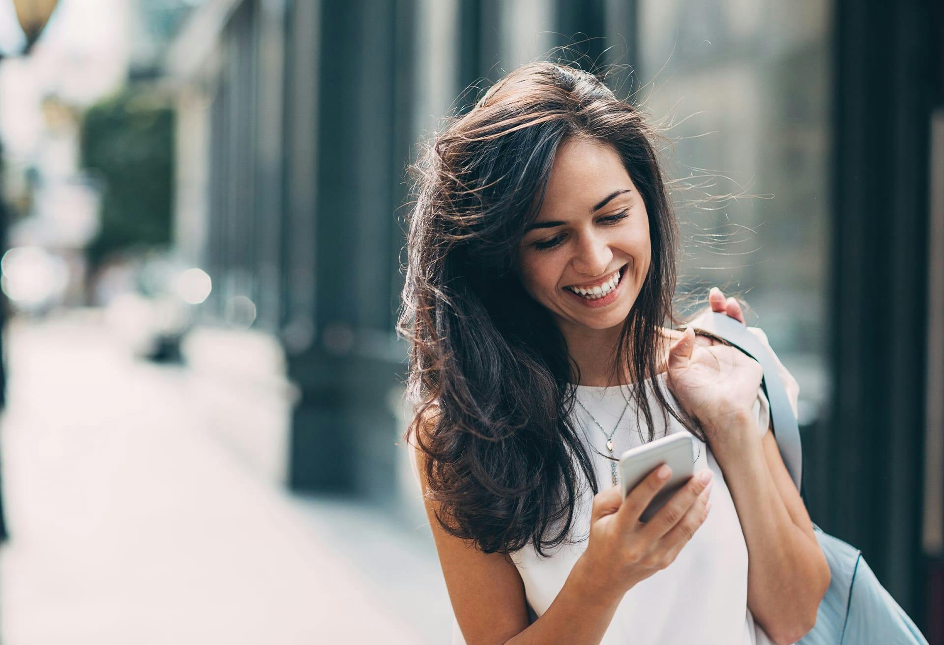 Woman Smiling and Looking at Her Phone