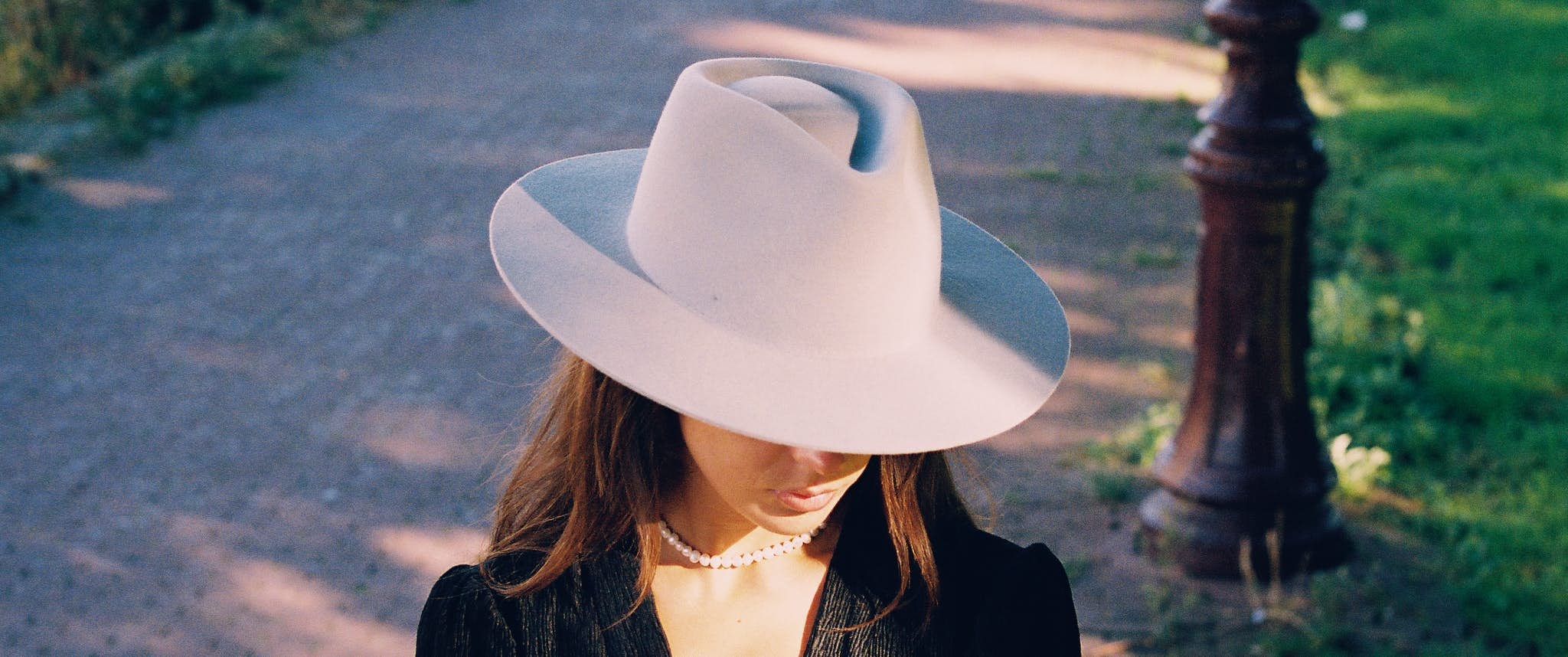 Girl looking down wearing a Sui Generis hat.