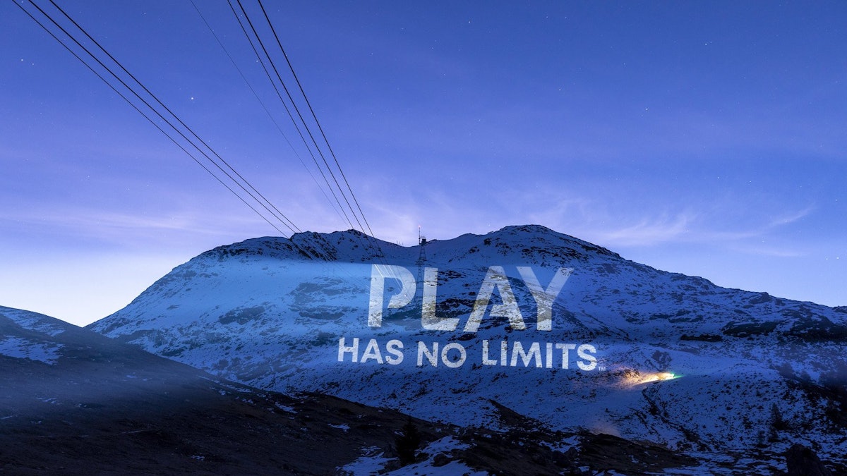 “Play Has No Limits” projected across a snow-covered mountainside at St. Moritz at dusk.