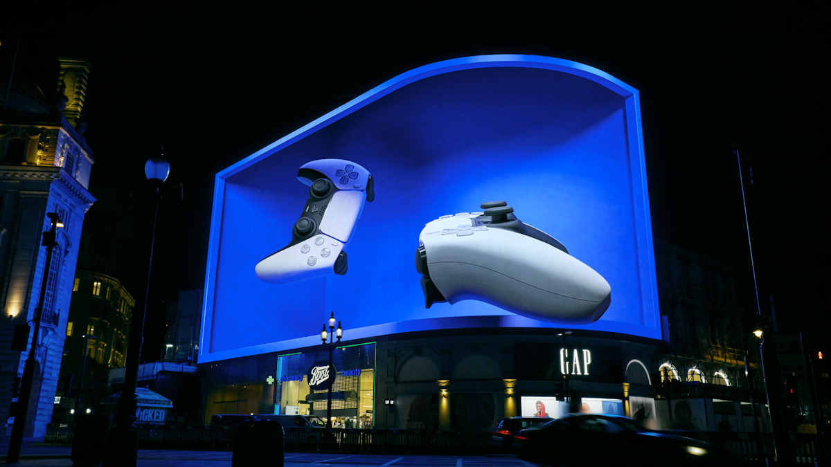 The PlayStation 5 launch takeover at Piccadilly Circus, London: a giant curved 3D billboard showing a DualSense controller glowing over the night-time square.
