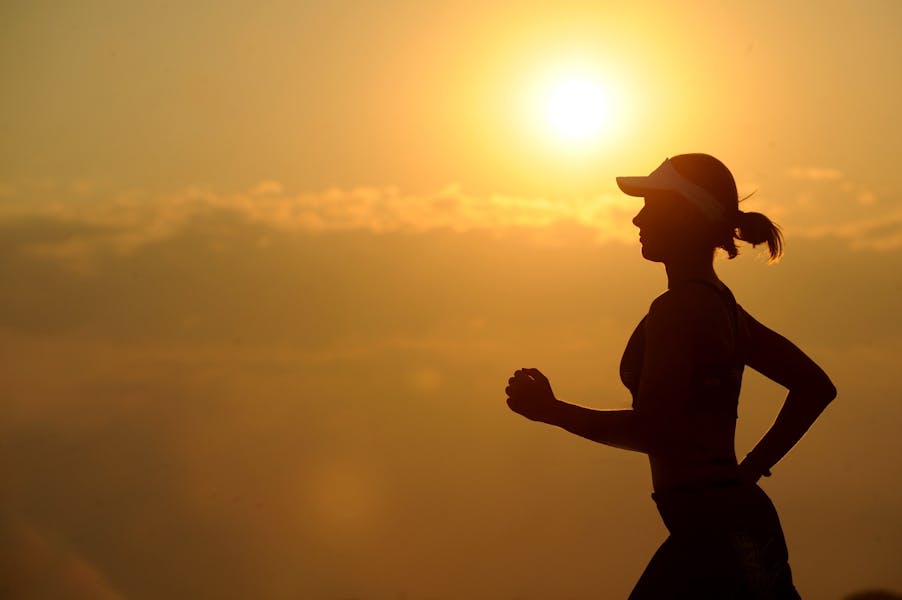 Profile of woman running in the sunset.