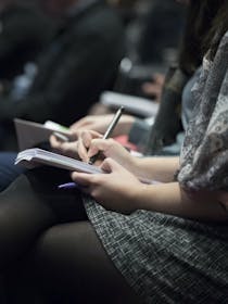 selective focus photography of people sitting on chairs while writing on notebooks