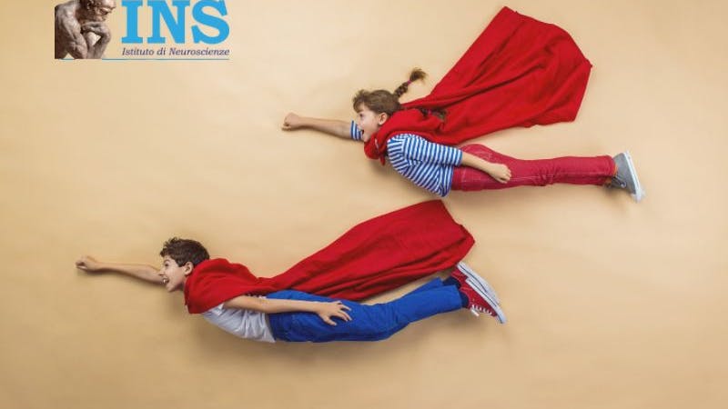 Two  children wear superhero capes and pose as if they are flying.