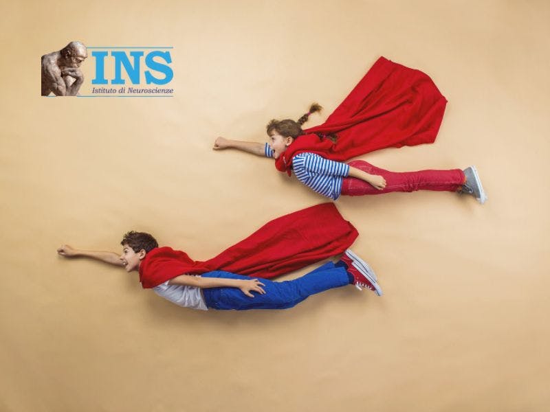Due bambini indossano dei mantelli da supereroe e sono in posa come se stessero volando.