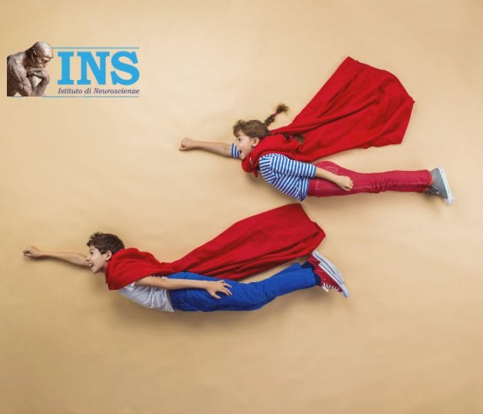 Two  children wear superhero capes and pose as if they are flying.