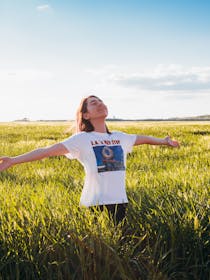 Una ragazza a braccia aperte si gode il sole in un campo di grano appena tagliato