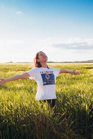 Una ragazza a braccia aperte si gode il sole in un campo di grano appena tagliato
