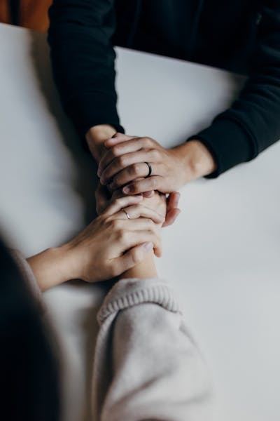 Two people holding their hands on a table.