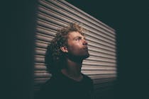 man leaning on gray painted wall