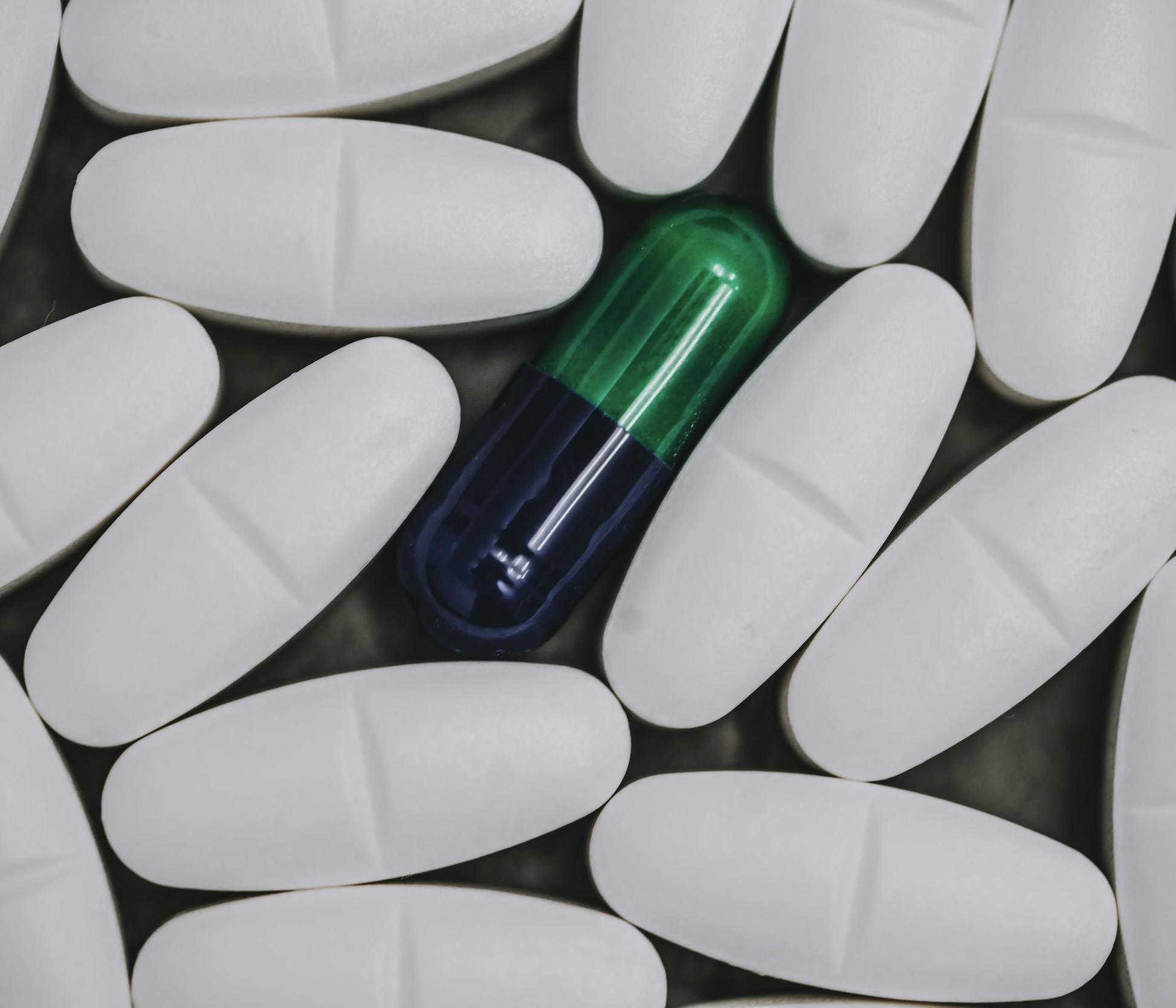 Pillole bianche circondano una pillola verde e nera