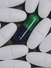 Pillole bianche circondano una pillola verde e nera