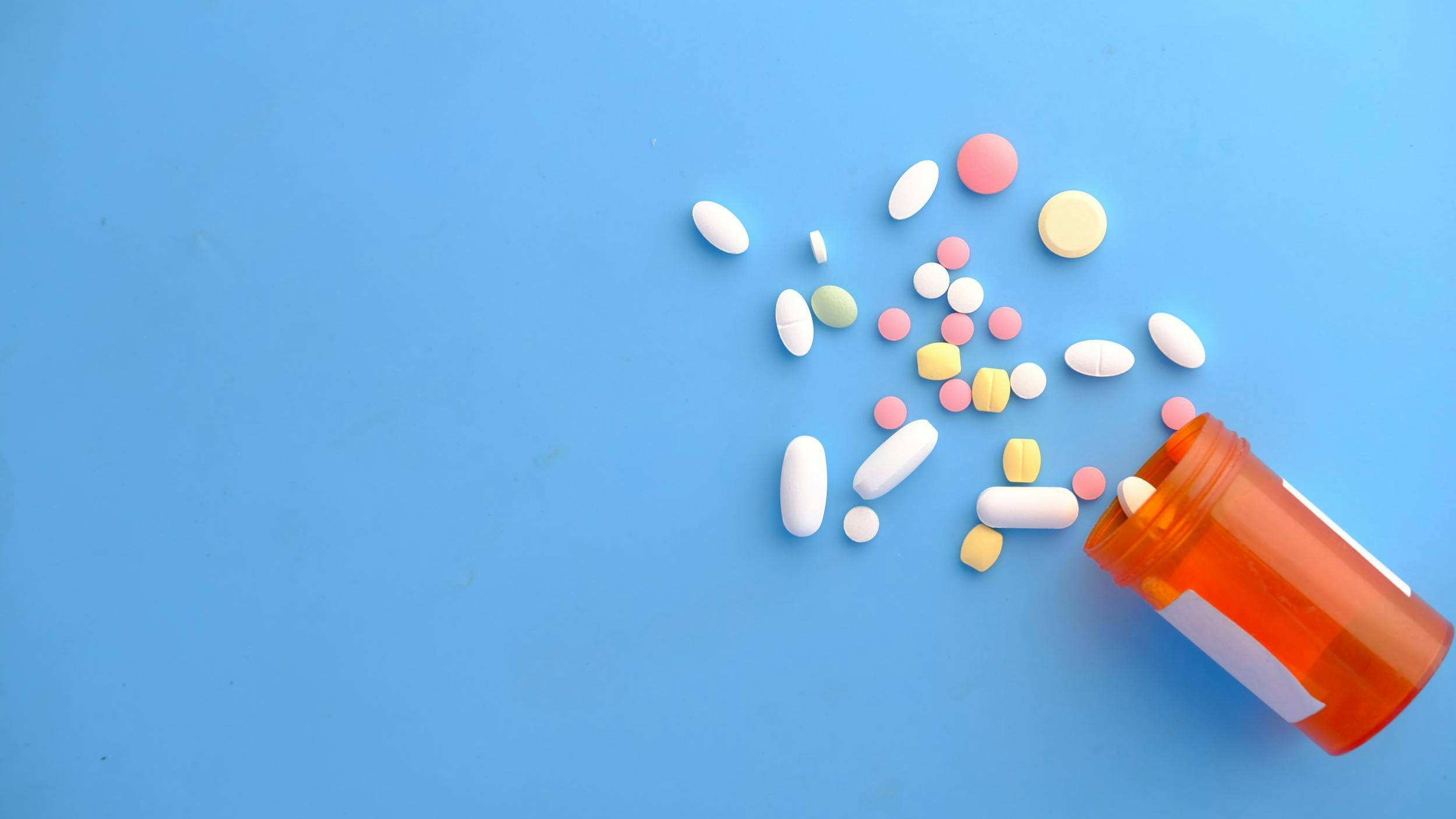 Pasticche di diversi farmaci fuori dalla confezione su sfondo blu