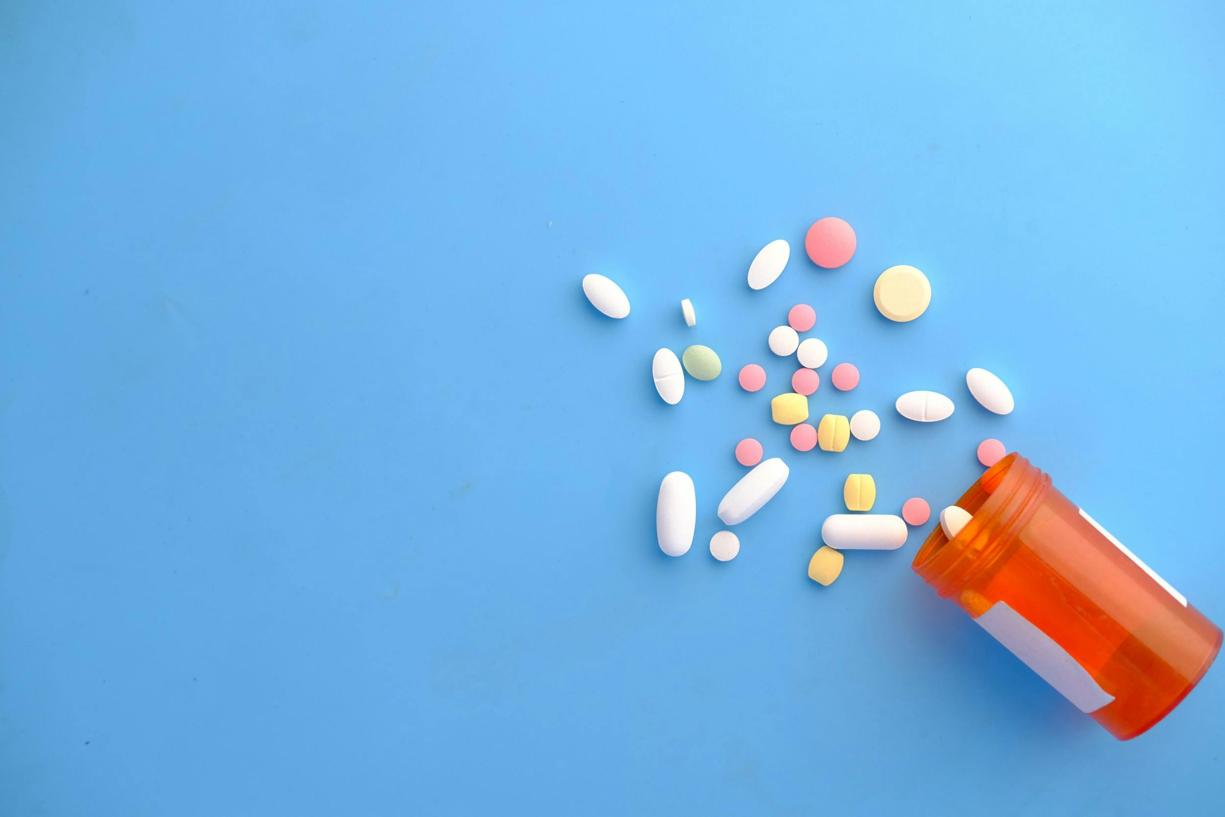 Pasticche di diversi farmaci fuori dalla confezione su sfondo blu