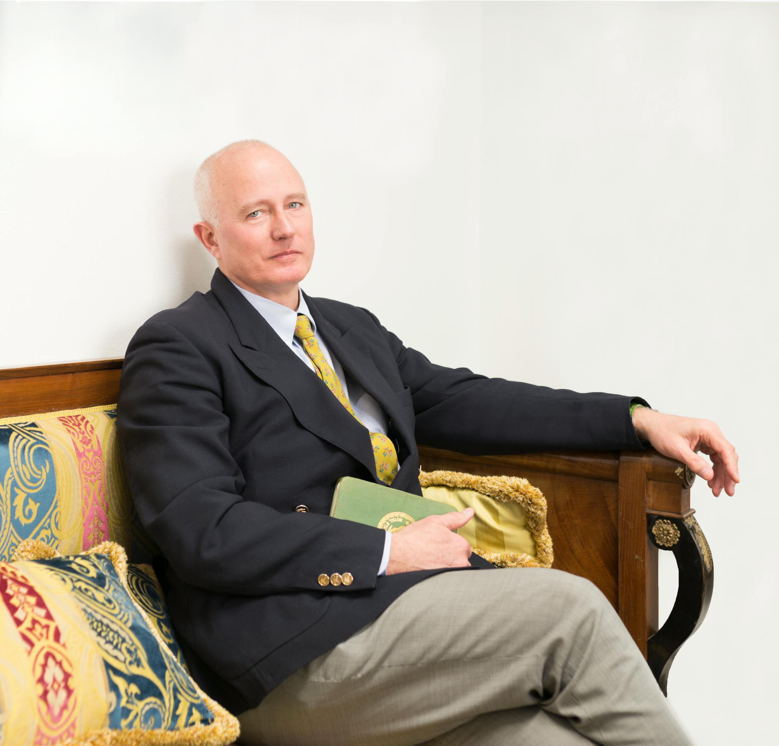 Photo of Dr. Stefano Pallanti sitting in a vintage wooden armchair.