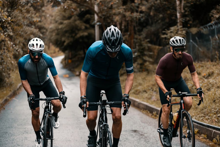 Foto di tre ciclisti che pedalano in salita