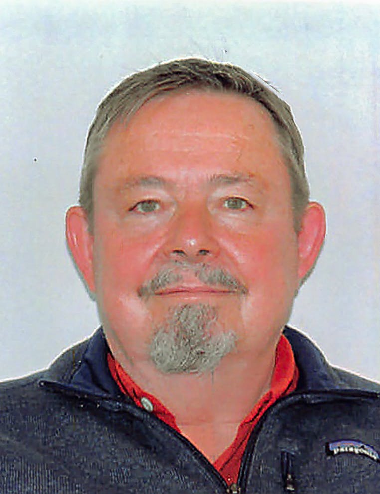 Picture of a smiling man with grizzled hair, mustache and goatee on a white background.