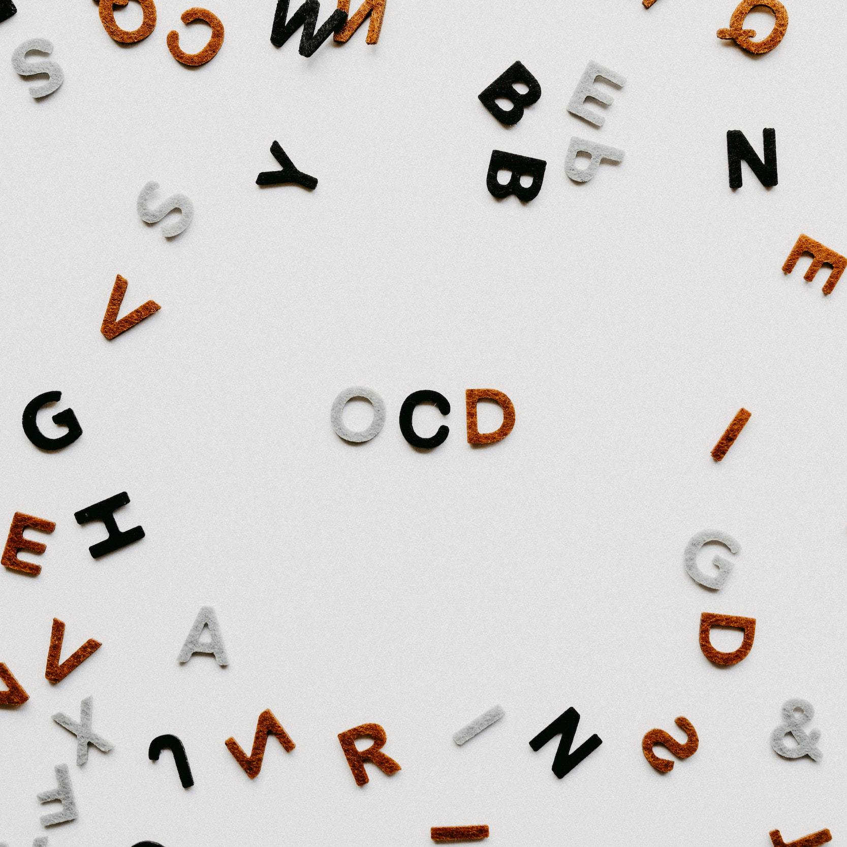 Scritta "OCD" che compare al centro di molte altre lettere sparse.