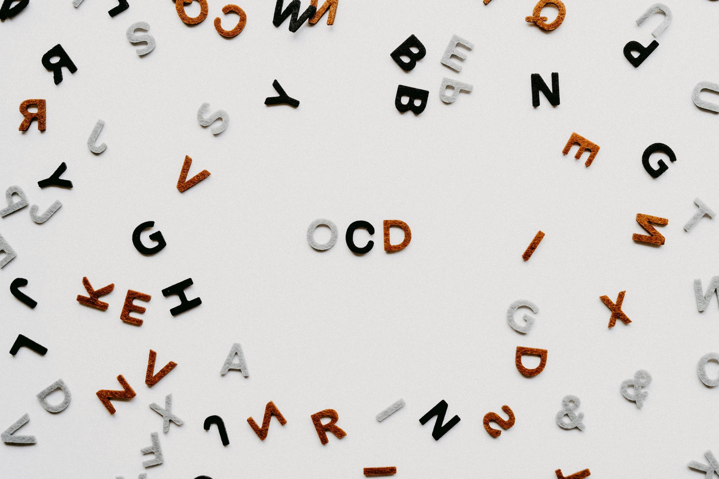 Scritta "OCD" che compare al centro di molte altre lettere sparse.