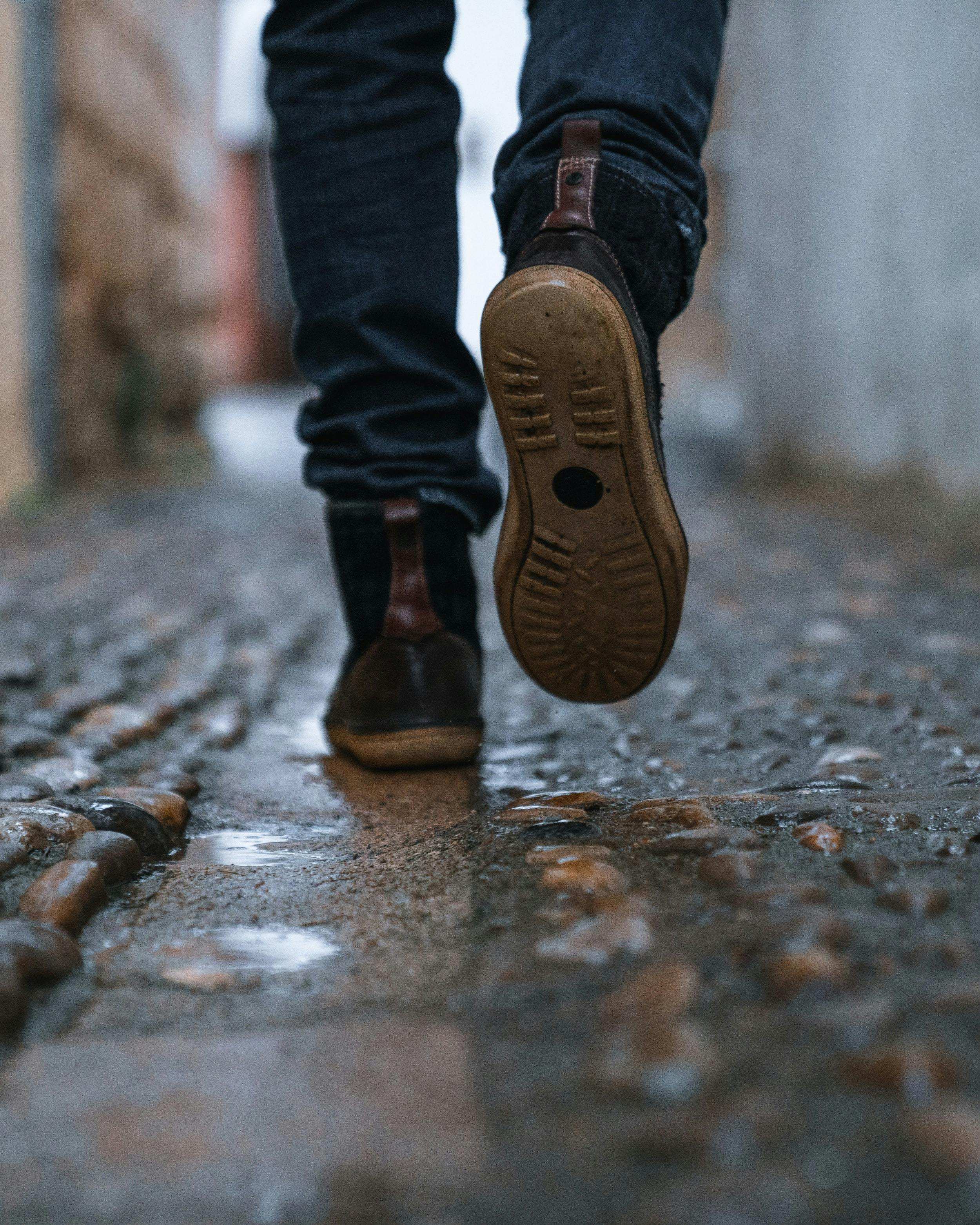 Primo piano di piedi di persona che cammina in un vicolo di una città.