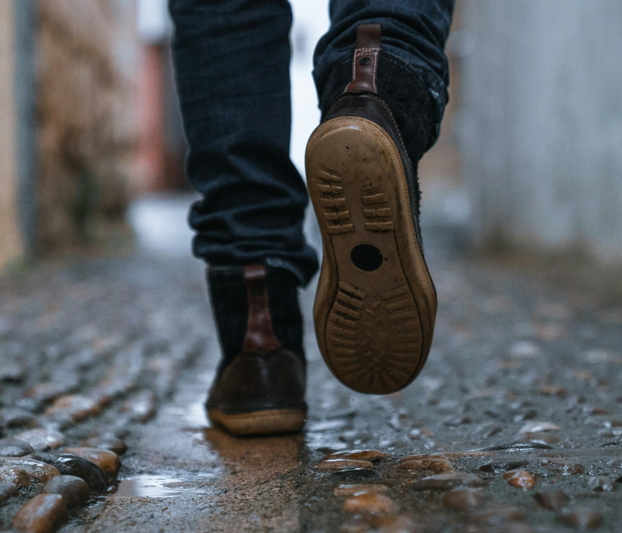 Primo piano di piedi di persona che cammina in un vicolo di una città.
