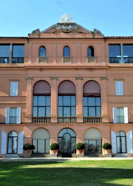 Villa settecentesca a 4 piani di colore arancio-rosa situata in mezzo al verde.