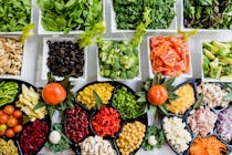 Una moltitudine di piatti contenenti diversi tipi di verdura, legumi e frutta
