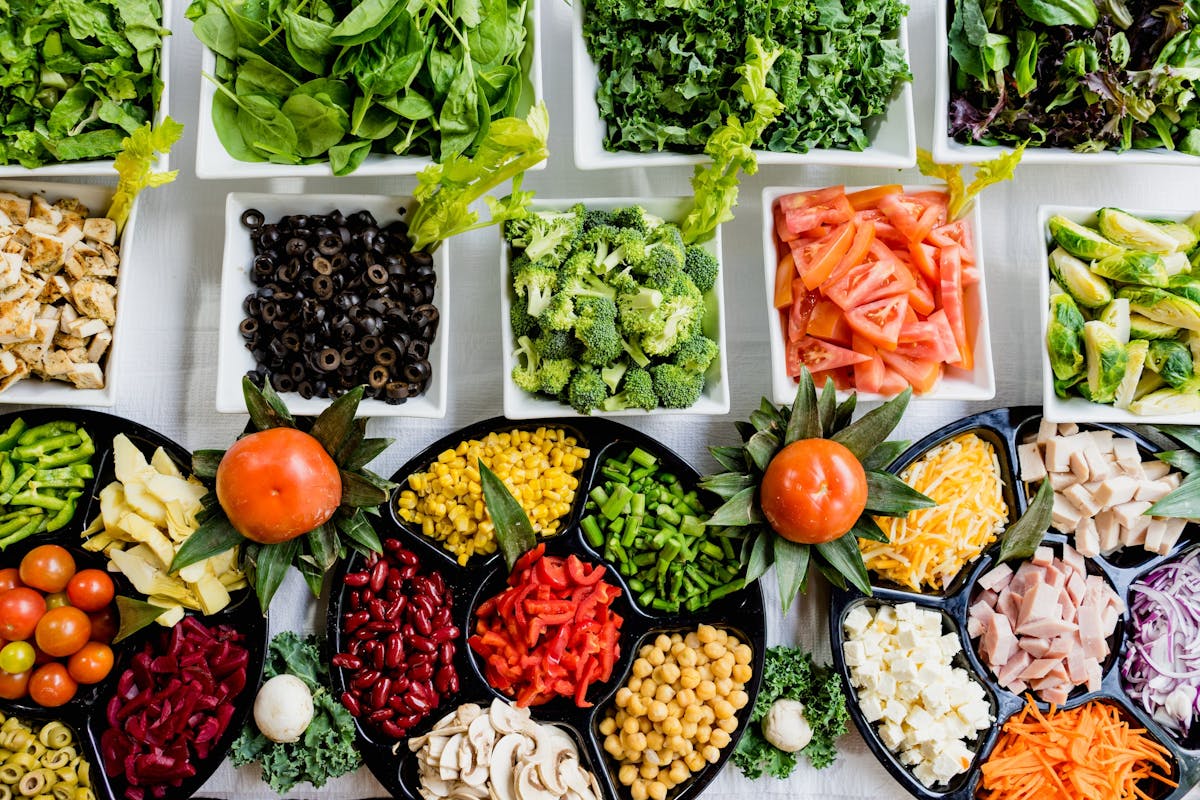 Una moltitudine di piatti contenenti diversi tipi di verdura, legumi e frutta