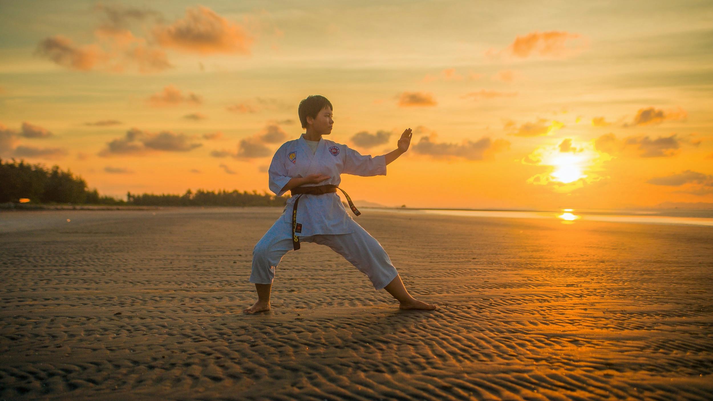 Ragazzo impegnato in una sessione di Karate sulla spiaggia durante il tramonto