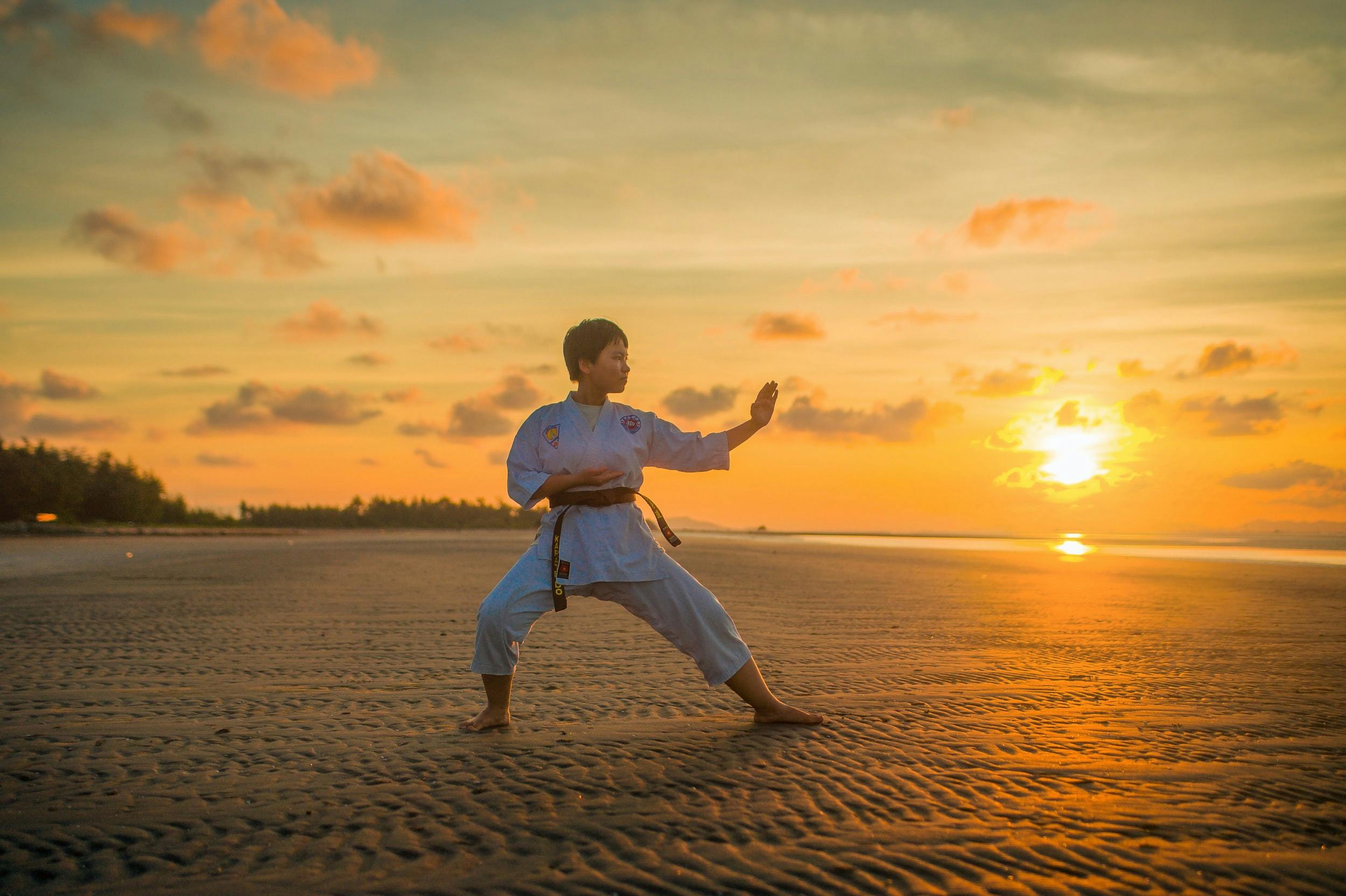 Ragazzo impegnato in una sessione di Karate sulla spiaggia durante il tramonto