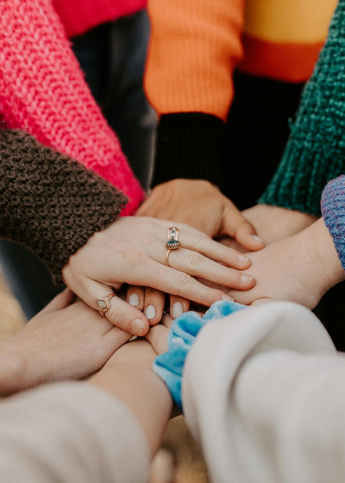 Photograph of several people's hands placed on top of each other as a sign of unity.
