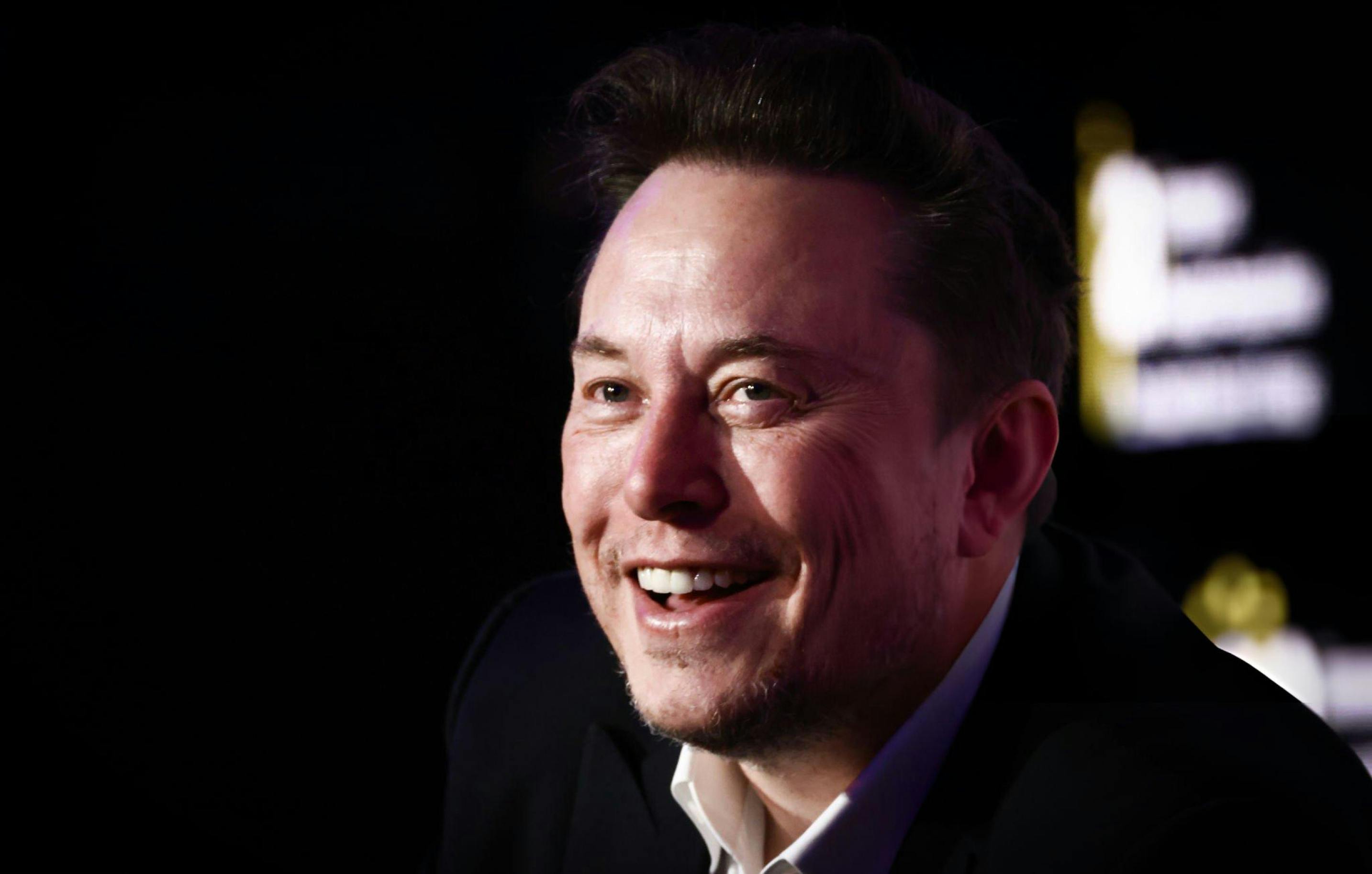 Fotografia di Elon Musk leggermente di profilo mentre sorride.