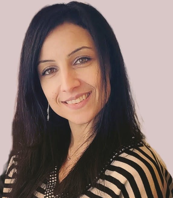 Light-skinned woman with black hair and brown eyes looking smiling into the camera.