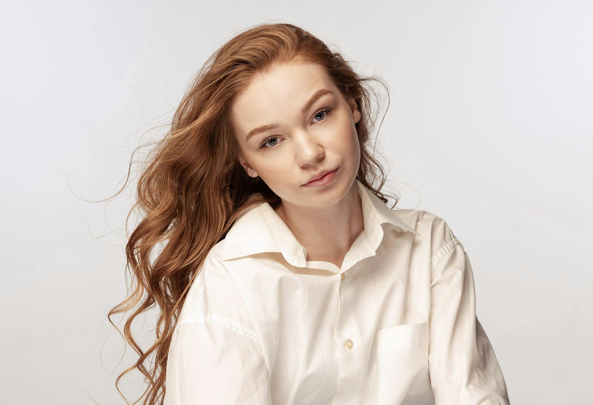 there is a woman with long hair sitting down and looking at the camera