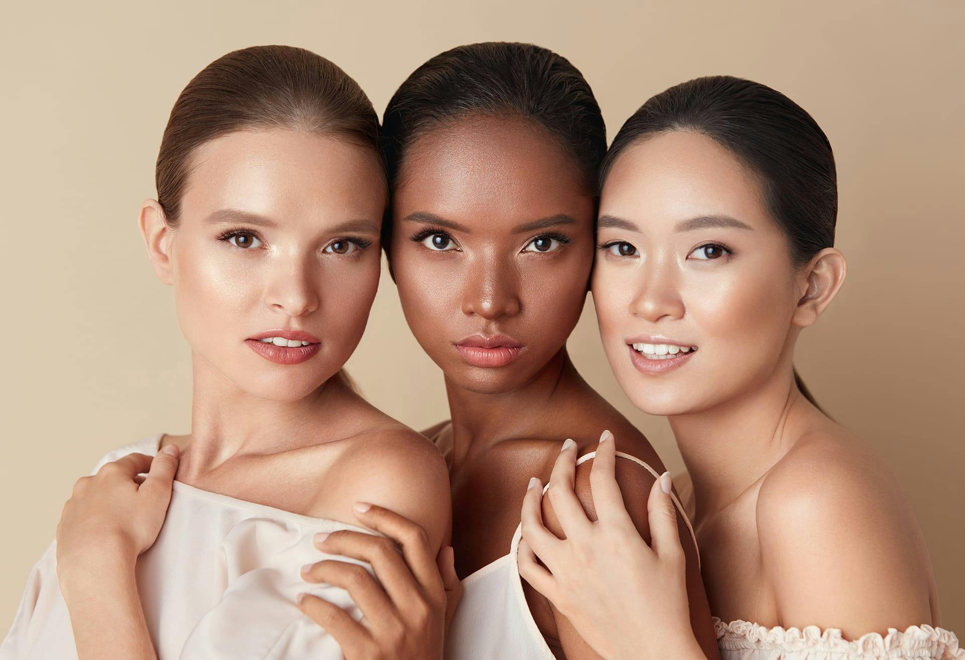three women in white dresses posing for a picture with their hands on their shoulders