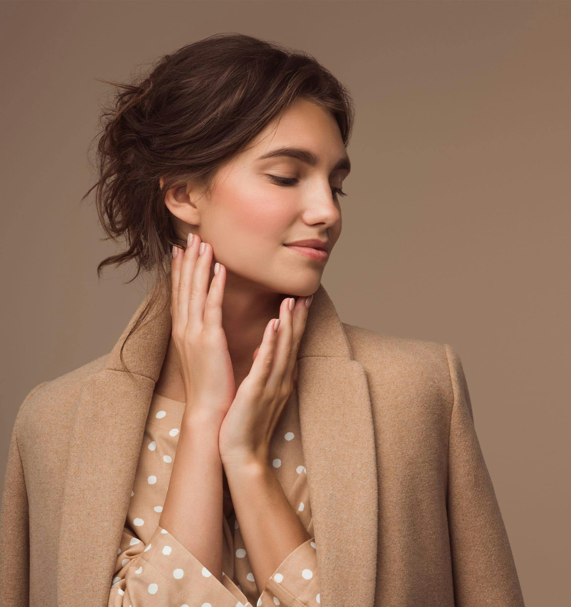 woman in a tan coat and polka dot shirt posing for a picture