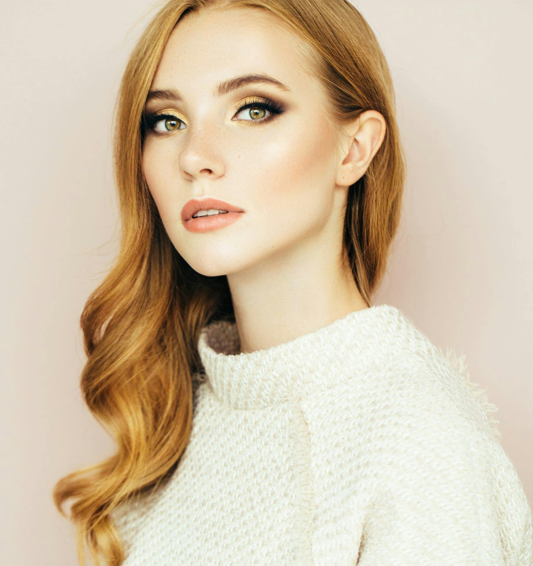 woman with long red hair and a white sweater
