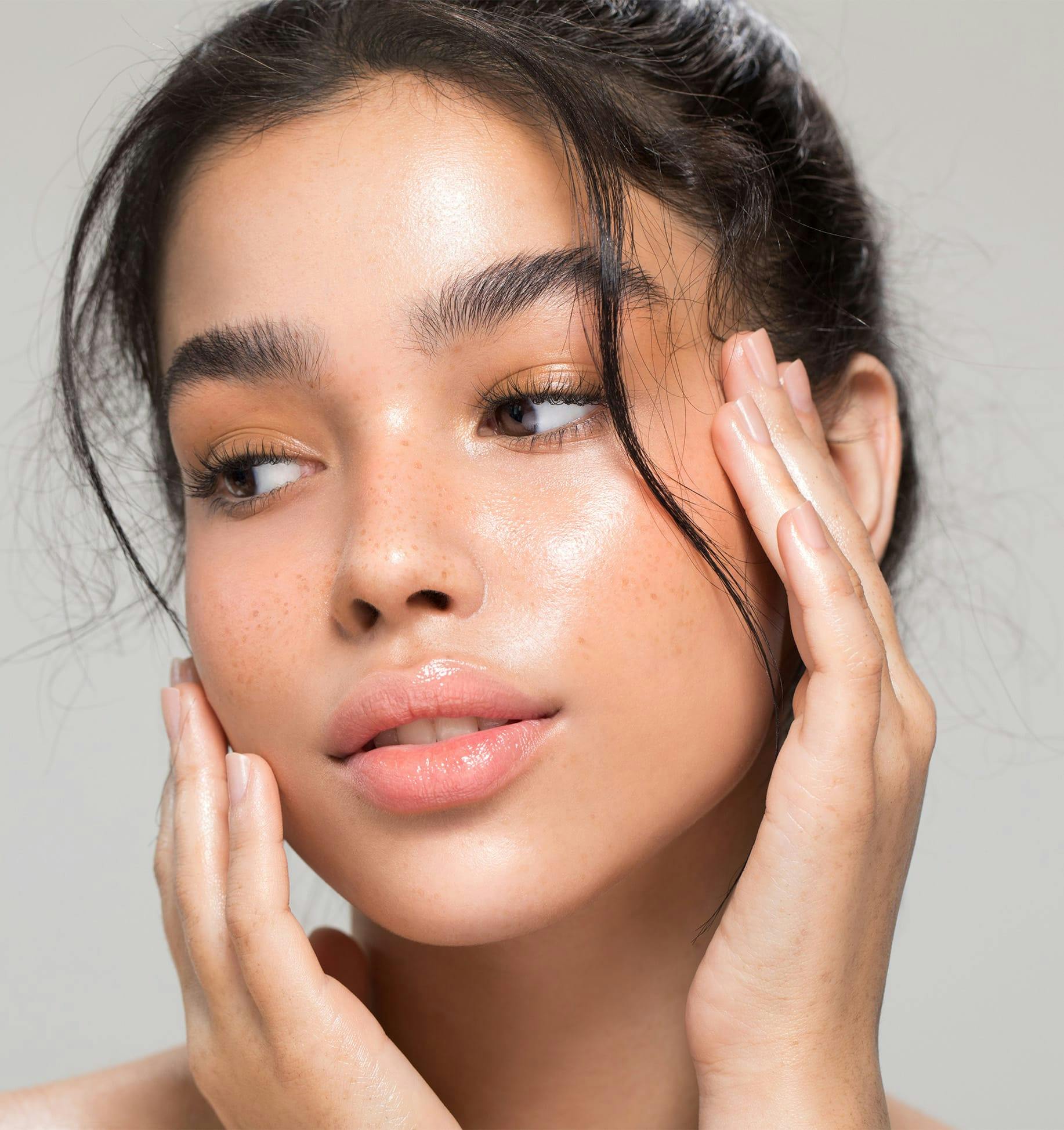 woman with freckles touching face